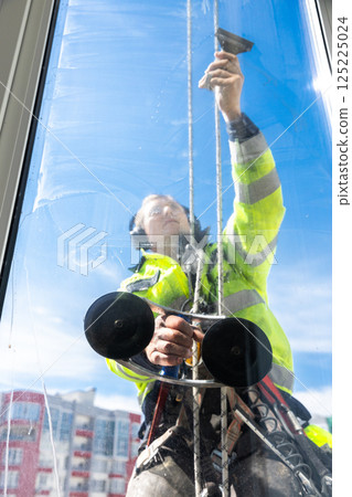 Dedicated Window Cleaner Scaling Heights to Ensure Crystal Clear Views in Abodes with Bright Blue Skies in the Background 125225024