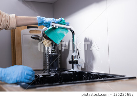 A Close-Up of a Person Cleaning the Kitchen Sink with a Cotton Cloth, Demonstrating Home Maintenance and Hygiene Practices for a Sparkling Clean Surface 125225692