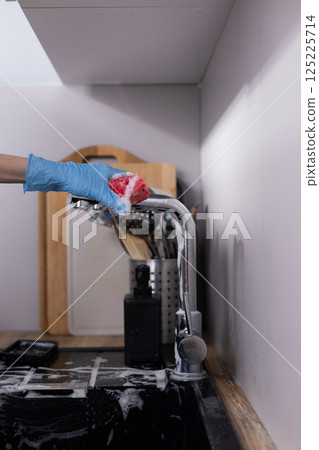 Cleaning the Kitchen Sink with Soapy Sponge: A Detailed Look at the Dishwashing Routine in a Modern Home 125225714