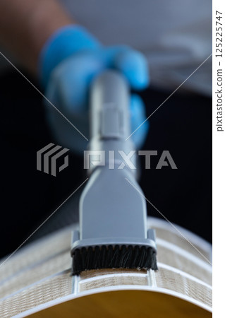 Close-Up of a Hand Using a Vacuum Attachment on a Household Item for Efficient Cleaning and Dust Extraction with Precision and Care Close-Up of a Hand Using a Vacuum Attachment on a Household Item for Efficient Cleaning and Dust Extraction with Precision and Care 125225747