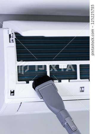 Essential Air Conditioner Maintenance: Cleaning the Dust Filter with a Brush Attachment for Enhanced Cooling Efficiency and Improved Air Quality in Your Home 125225785