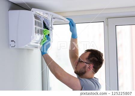 Expert Maintenance on Air Conditioning Unit: A Professional Cleans and Maintains HVAC System for Optimal Performance and Air Quality Management in a Modern Space Expert Maintenance on Air Conditioning Unit: A Professional Cleans and Maintains HVAC System for Optimal Performance and Air Quality Management in a Modern Space 125225807
