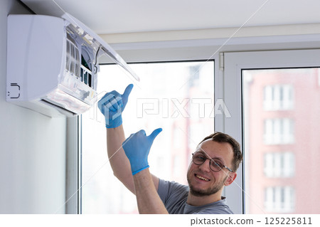 Professional Technician Installing Air Conditioner with Precision and Care, Showcasing Excellent Skill with Thumbs Up Gesture While Working in Bright, Modern Living Space Professional Technician Installing Air Conditioner with Precision and Care, Showcasing Excellent Skill with Thumbs Up Gesture While Working in Bright, Modern Living Space 125225811