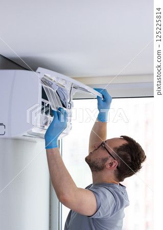 Professional Technician Performing Maintenance on Air Conditioning Unit: Importance of Regular Servicing for Optimal Performance and Efficiency in Modern Indoor Environments 125225814