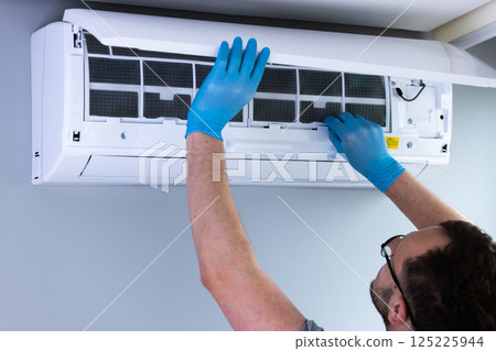 Technician Performing Maintenance on an Air Conditioning Unit: Ensuring Optimal Performance and Indoor Air Quality Care During Filter Replacement in Residential Spaces Technician Performing Maintenance on an Air Conditioning Unit: Ensuring Optimal Performance and Indoor Air Quality Care During Filter Replacement in Residential Spaces 125225944