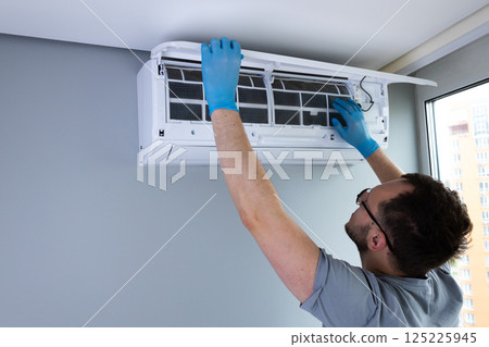Professional Installation of Air Conditioning Unit by Skilled Technician with Protective Gloves Indoors for Optimal Climate Control in Modern Residential Space Professional Installation of Air Conditioning Unit by Skilled Technician with Protective Gloves Indoors for Optimal Climate Control in Modern Residential Space 125225945
