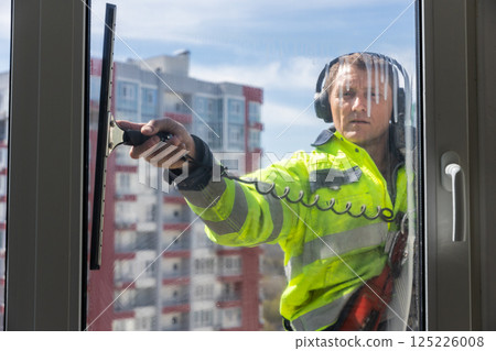 Professional Window Cleaner in Action: Ensuring Clear Views and Safety in Urban Environment with a Reflective Skyline as the Backdrop for an Expert Cleaning Service Professional Window Cleaner in Action: Ensuring Clear Views and Safety in Urban Environment with a Reflective Skyline as the Backdrop for an Expert Cleaning Service 125226008