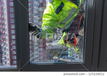 Window Cleaning Professional Maintaining Bright and Clear Panes on a Tall Building in a Vibrant Cityscape with Reflective Glass and a Diligent Worker in Safety Gear 125226012