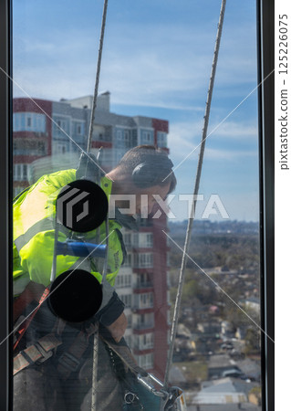 A Dedicated Window Cleaner at Work, Ensuring Crystal-Clear Views from Sky-High Locations While Taking Precautions for Safety and Efficiency in Urban Settings A Dedicated Window Cleaner at Work, Ensuring Crystal-Clear Views from Sky-High Locations While Taking Precautions for Safety and Efficiency in Urban Settings 125226075