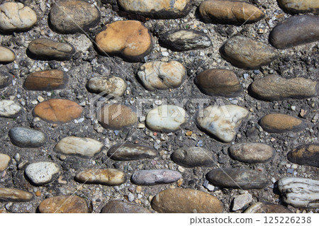 Close-up of cobblestone pavement texture with natural stones in dry soil 125226238