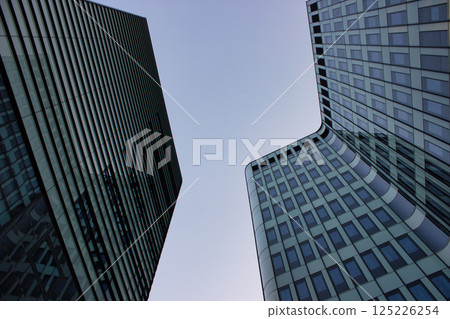 Modern glass skyscrapers curve into clear morning sky 125226254