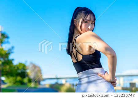 The back view of a cool woman exercising under the blue sky, looking back, diet, exercise, exercise, trimming The back view of a cool woman exercising under the blue sky, looking back, diet, exercise, exercise, trimming 125226747