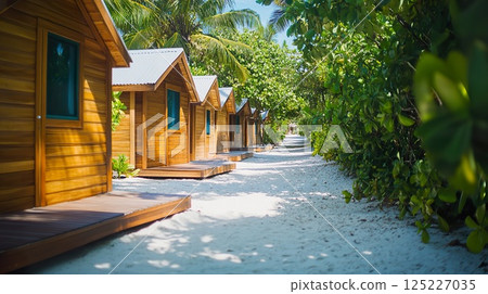 Rustic bungalows line sandy path, surrounded by lush tropical foliage. 125227035