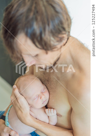 Father cuddling his sleeping newborn son skin-to-skin. Tender parental bonding and newborn care. Fatherhood, love, and early parent-child connection concept 125227494