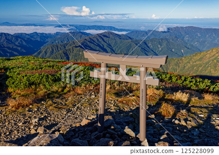 Torii gate and morning mountain range at the summit of Mt. Kitamata in the Iide mountain range 125228099