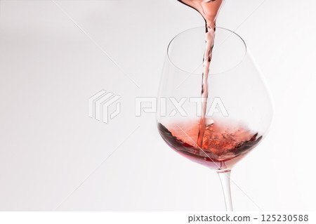 Red wine poured into a glass 125230588