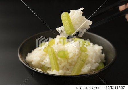 用筷子夾起在陶罐裡煮好的款冬飯 用筷子夾起在陶罐裡煮好的款冬飯 125231867