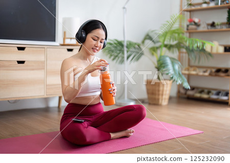 Wellness and Hydration. A woman enjoying a refreshing drink to support her fitness routine. 125232090