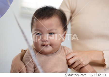 Pediatric doctor interacting with baby during a check up while parent supports child. Pediatric doctor interacting with baby during a check up while parent supports child. 125232111