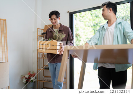 LGBTQ couple happily moving furniture into their new home, showcasing love and partnership. 125232334