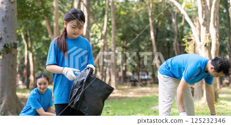 Diverse family volunteering for garbage collection in a park, promoting environmental awareness and community service. 125232346