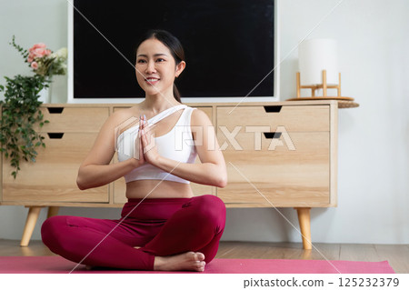Yoga and Exercise. A woman practicing yoga, seated cross-legged in a meditative posture on a yoga mat, promoting mindfulness and relaxation. 125232379