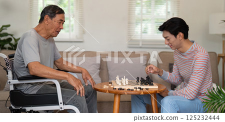 Father and son enjoying a chess match in a cozy living room, emphasizing family connection and strategic play. 125232444
