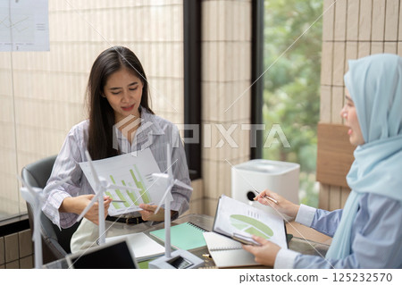 Data Analysis and Sustainable Design. A woman reviewing graphs and models for a green project in a collaborative setting. 125232570