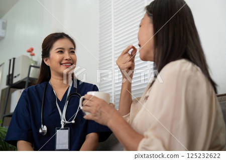 Patient Consultation and Friendly Care. A caregiver engages with an elderly woman, discussing medication while providing encouragement during their conversation. Patient Consultation and Friendly Care. A caregiver engages with an elderly woman, discussing medication while providing encouragement during their conversation. 125232622