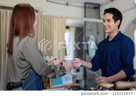 Customer Interaction and Eco-Friendly Initiatives. A barista passing a drink to a customer, emphasizing sustainability. Customer Interaction and Eco-Friendly Initiatives. A barista passing a drink to a customer, emphasizing sustainability. 125232637