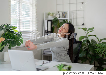 Wellness and Stretching. A woman takes a moment to stretch during her work-from-home routine. Wellness and Stretching. A woman takes a moment to stretch during her work-from-home routine. 125232667