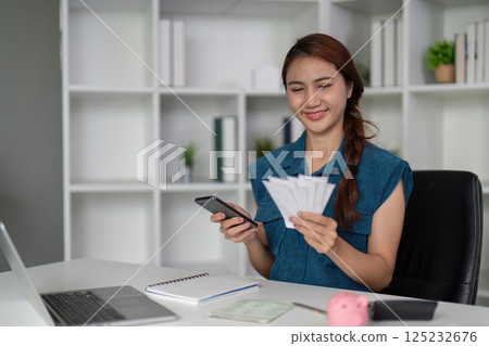 Financial Planning and Savings. A woman happily managing her finances by reviewing her savings and holding cash. 125232676
