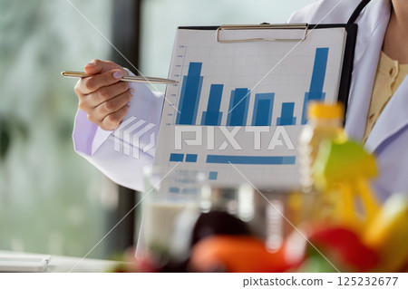 Nutrition and Health Analysis. A healthcare professional presenting nutritional data and graphs to guide dietary decisions. 125232677