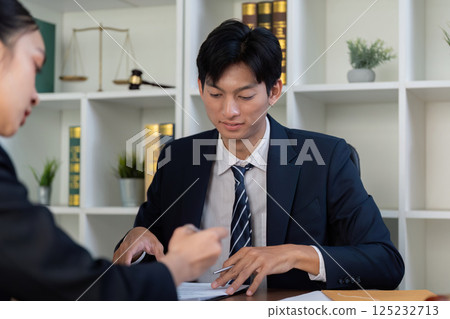 Consultation and Legal Advice. An attorney meeting with a client to review documents. 125232713