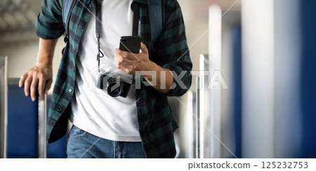 Travel and Photography. A young man with a camera checks his phone while exploring a train. Travel and Photography. A young man with a camera checks his phone while exploring a train. 125232753