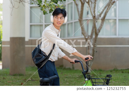 Awareness and Mobility in Urban Landscapes. A person pauses on their bicycle, looking back in a thoughtful manner. Awareness and Mobility in Urban Landscapes. A person pauses on their bicycle, looking back in a thoughtful manner. 125232755