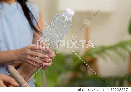 Collaborative Waste Sorting. A mother and daughter work together, learning about recycling and sustainability in their living room setting. 125232817