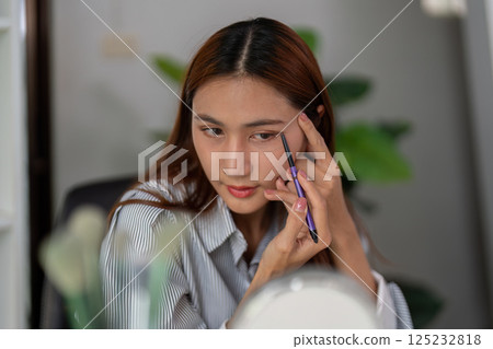 Eye Makeup and Precision. A woman skillfully applying eyeliner for a polished look. Eye Makeup and Precision. A woman skillfully applying eyeliner for a polished look. 125232818