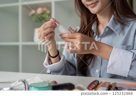 Makeup Routine and Skincare Essentials. A woman prepares to apply foundation while focusing on her beauty regimen. 125232868