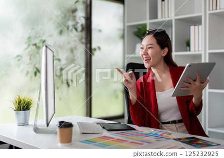 Graphic Design and Creativity. A designer engaging with digital art, showcasing vibrant color palettes on her tablet and desktop. 125232925