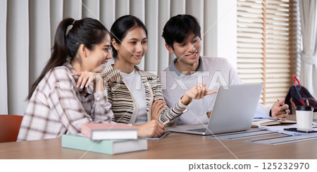 Teamwork and Learning. Three students collaborating on a project using a laptop in a bright and modern study space. 125232970