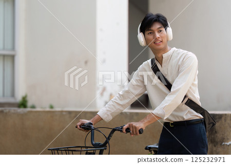 Cycling and Sustainable Living. A young individual rides a bicycle, embracing eco-friendly transportation while enjoying music. Cycling and Sustainable Living. A young individual rides a bicycle, embracing eco-friendly transportation while enjoying music. 125232971