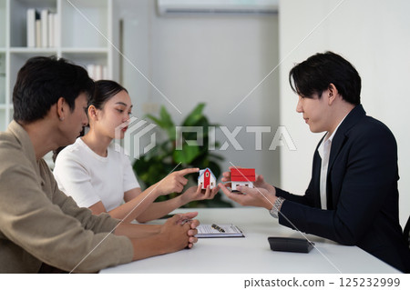 Consultation and Property Choices. A couple discusses housing options with their real estate agent. Consultation and Property Choices. A couple discusses housing options with their real estate agent. 125232999