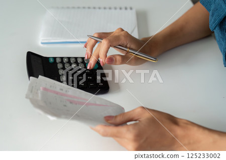 Financial Management and Budgeting. A person calculating expenses with a calculator and receipts for effective budgeting. 125233002