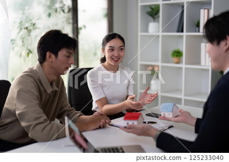 Consultation and Communication. A couple discusses their options while engaging with a real estate agent. 125233040