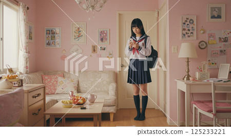 A high school girl operates her smartphone in her room, decorated in light pink. 125233221