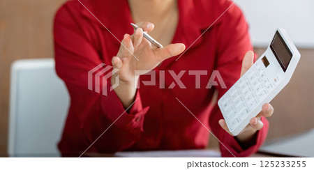 Calculating Finance Online. A professional actively engages in financial calculations while discussing reports. 125233255