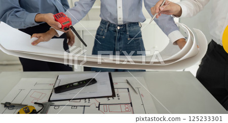 Teamwork and Project Discussion. Professionals examining detailed construction plans while focused on efficient building design. Teamwork and Project Discussion. Professionals examining detailed construction plans while focused on efficient building design. 125233301