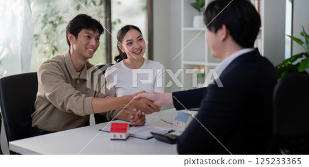 Successful Negotiation and Closing. A couple and their real estate agent finalize the home buying process. Successful Negotiation and Closing. A couple and their real estate agent finalize the home buying process. 125233365
