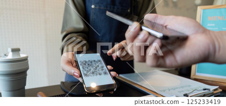 Digital Payments and Sustainable Choices in Action. A smartphone payment being facilitated at a coffee shop. 125233419
